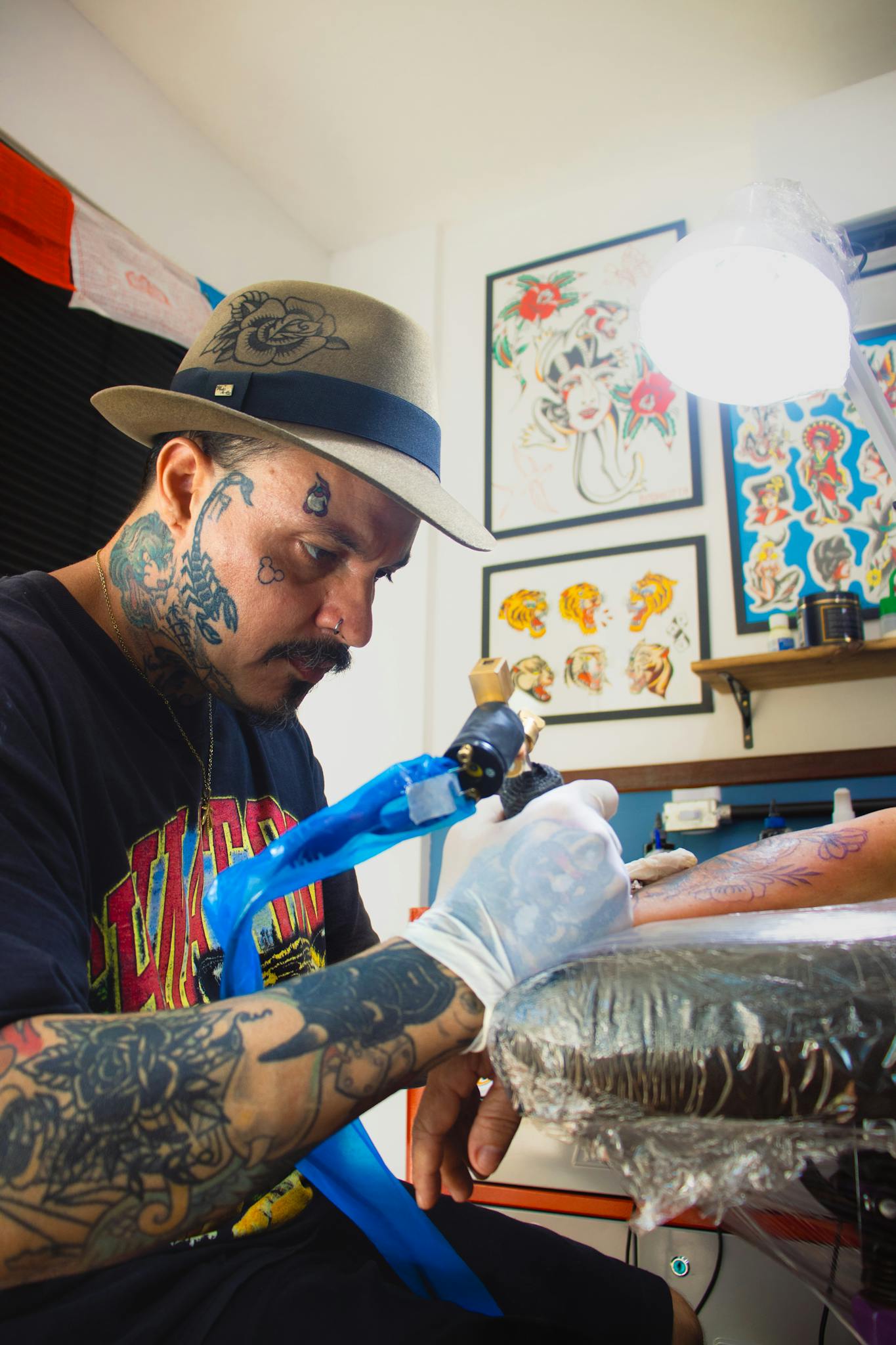 A skilled tattoo artist works on a client's arm, using a tattoo pen in a vibrant studio setting.