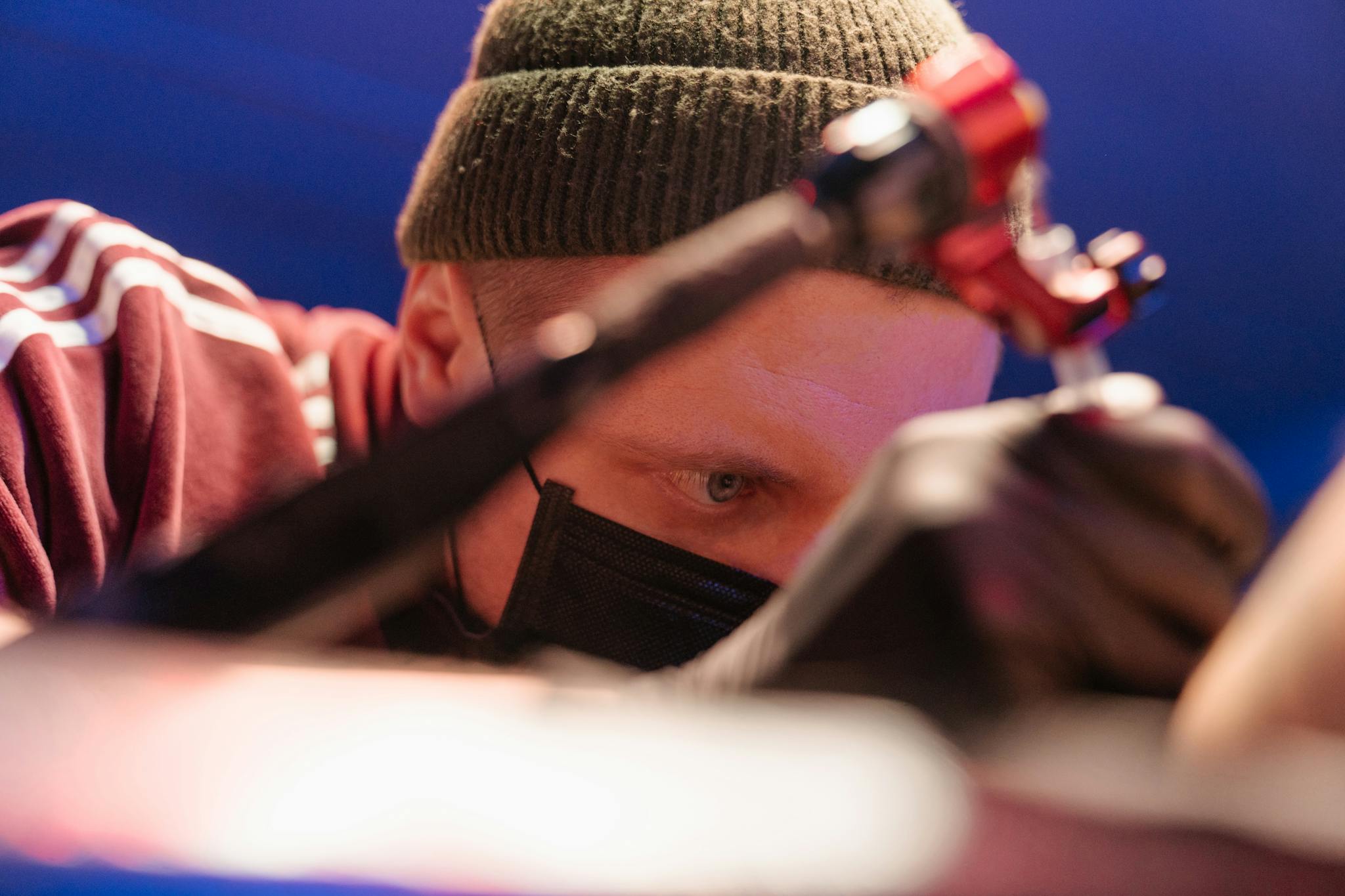 Close-up of a tattoo artist focused intently while working in a professional studio setting.